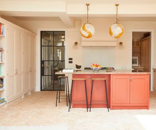 kitchen painted in soft peach with orange painted island unit