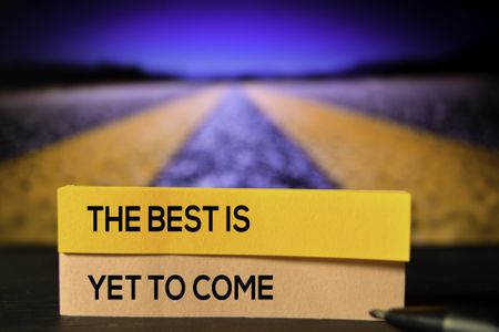 A road in the background with yellow lines to the distance, and small post-its saying "The best is yet to come" in block letters.