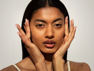 Woman with glowing skin touching her temples.