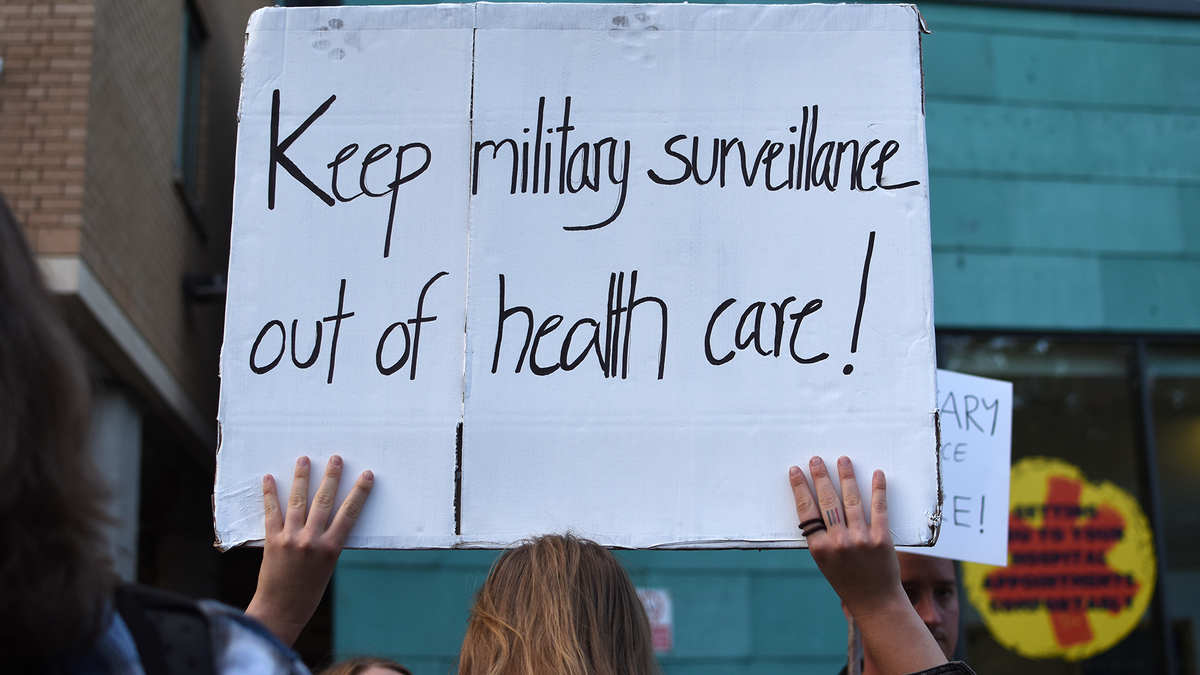 Woman holding placards against Palantir in the NHS in front of the Bristol Royal Infirmary during a protest on October 1, 2026