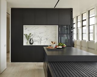 A black kitchen idea with a white marble alcove surrounded by black cabinetry and a black wooden island
