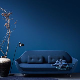 Fritz Hansen Favn JH-3 sofa in blue in a living room in front of a blue wall