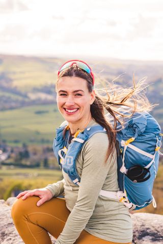 Hannah Walsh wearing a hiking backpack with the countryside in the background