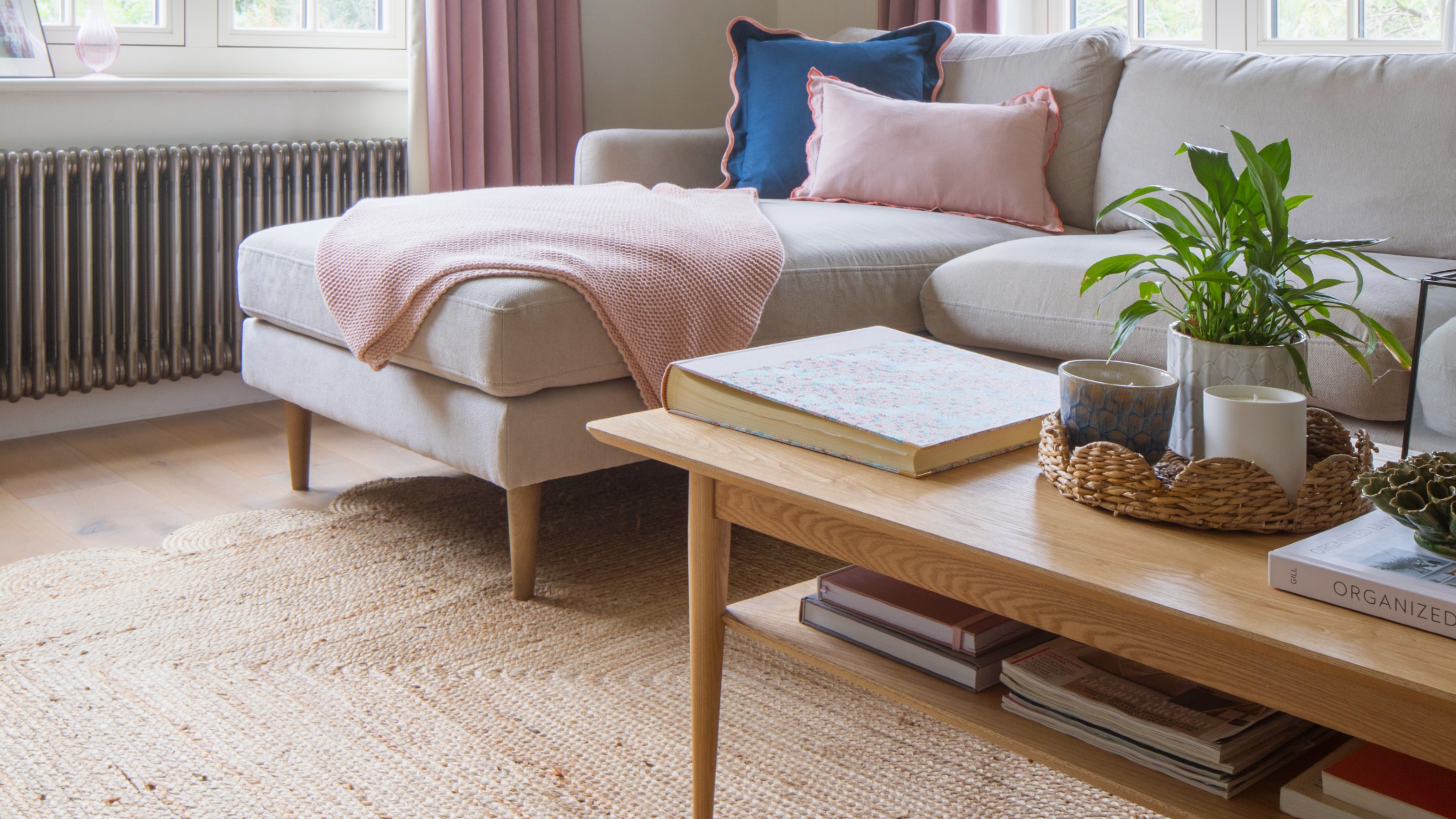 A living room with a neutral chaise sofa and a wooden rectangular coffee table with a storage shelf