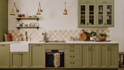a kitchen with green cabinetry, a checker-printed tile backsplash, and decor on the countertop