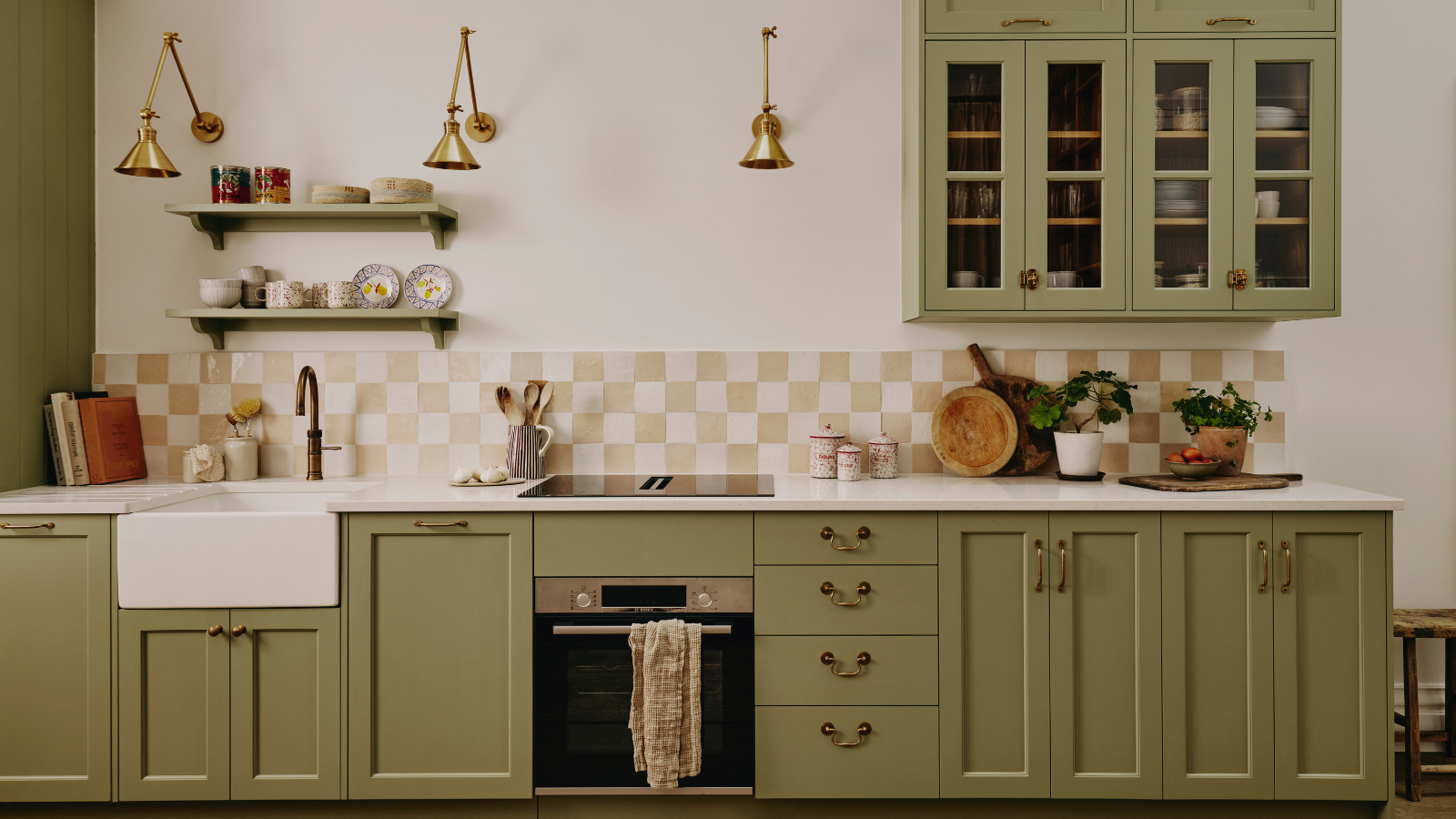 a kitchen with green cabinetry, a checker-printed tile backsplash, and decor on the countertop
