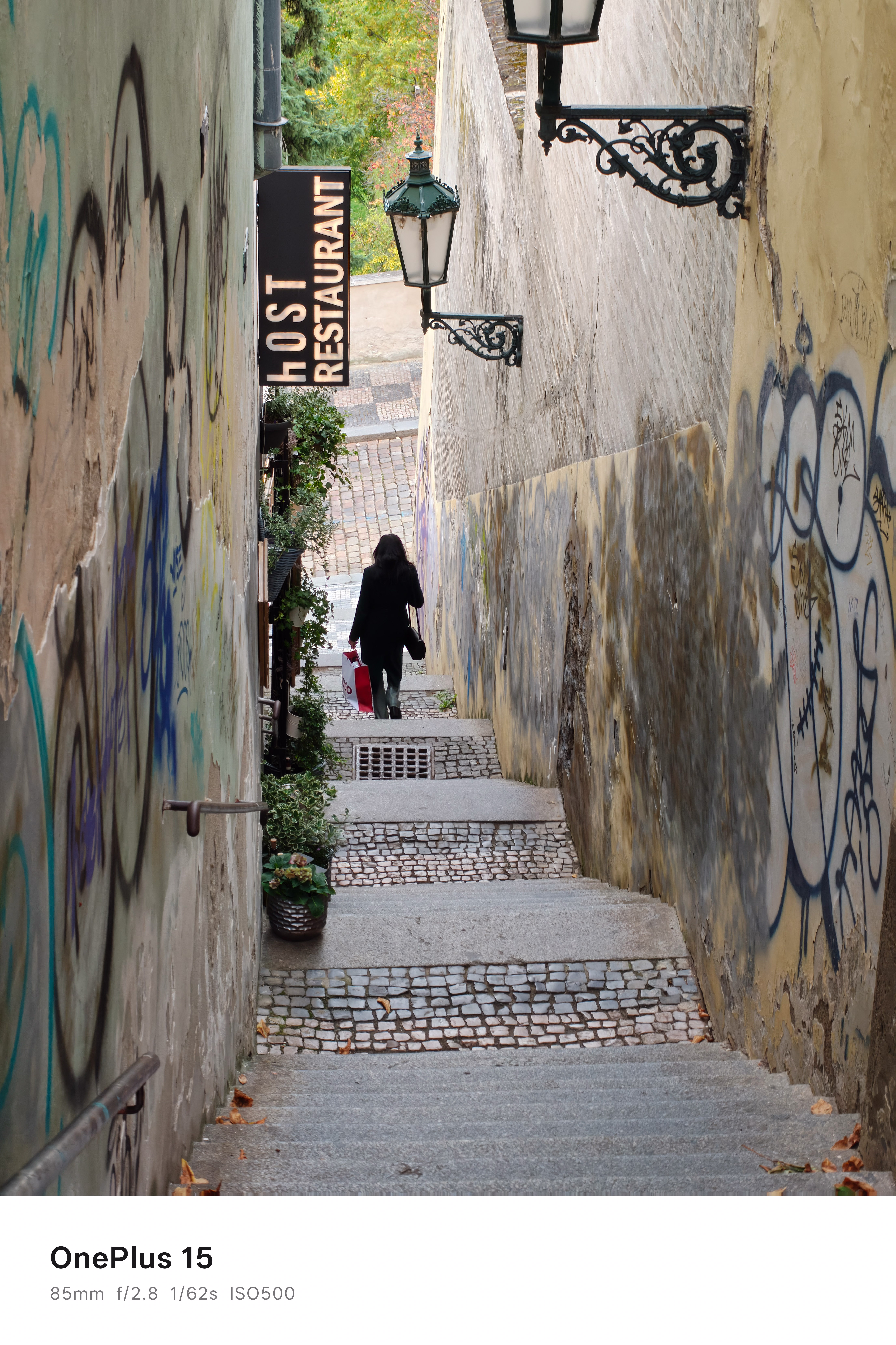A person walking down a narrow set of stone steps between two buildings in Prague
