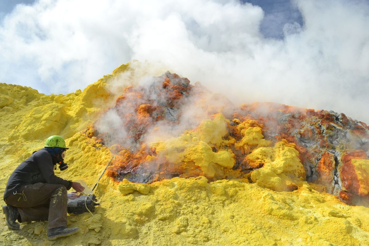 A gas-mask-clad researcher samples the CO2 emissions being released by Lastarria volcano in Chile. 