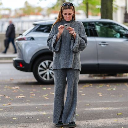 A guest wears black sunglasses, a grey wool turtleneck pullover, matchings pants, dark green sneakers shoes, during Womenswear Spring/Summer 2025 as part of Paris Fashion Week on September 30, 2024 in Paris, France. 