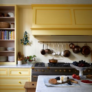 Yellow kitchen with wall panelling and a boxed in extractor fan over a hob