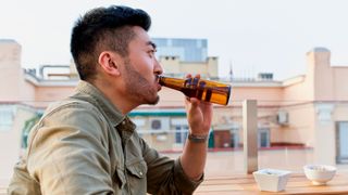 Man drinking from a bottle of beer in a bar