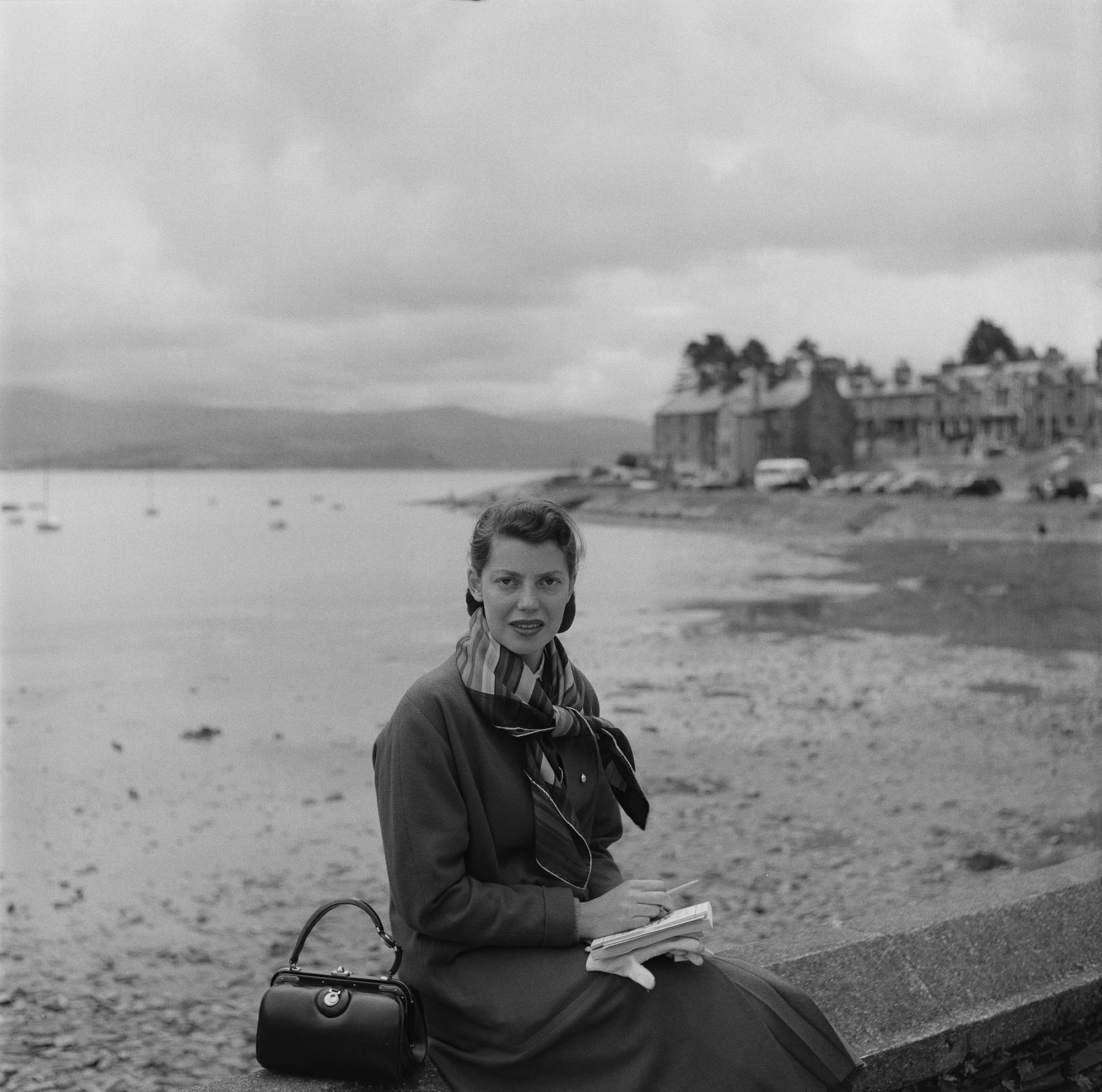 Rita Aarons, wife of photographer Slim Aarons, poses on a beach in Wales, 1957.