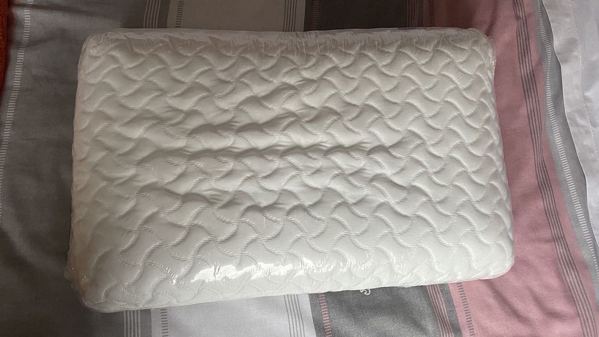 The Tempur-Pedic Tempur-Cloud pillow wrapped in plastic on a bed in the reviewer's home