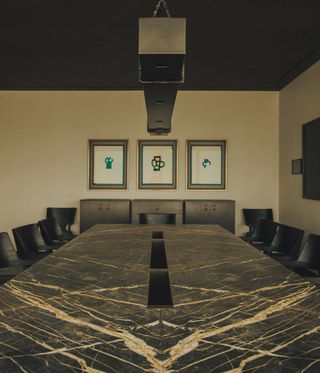 A large graphite / marble table with black chairs. Colour theme is predominantly dark grey and brown.