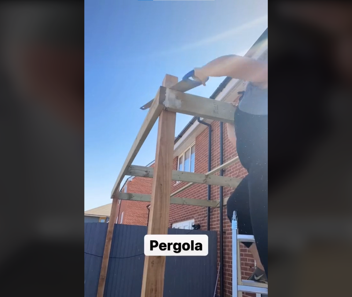 DIY pergola being put up in back garden by Jasmine on a ladder who was pregnant