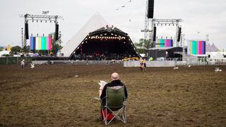A man reads his Sunday newspaper as revellers wake on the last day of the Glastonbury Festival of Music and Performing Arts 