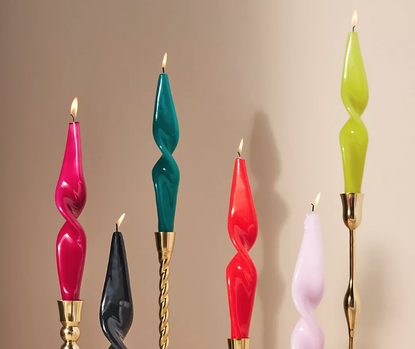 colorful twisted glossy candles stacked at different heights on gold candlesticks
