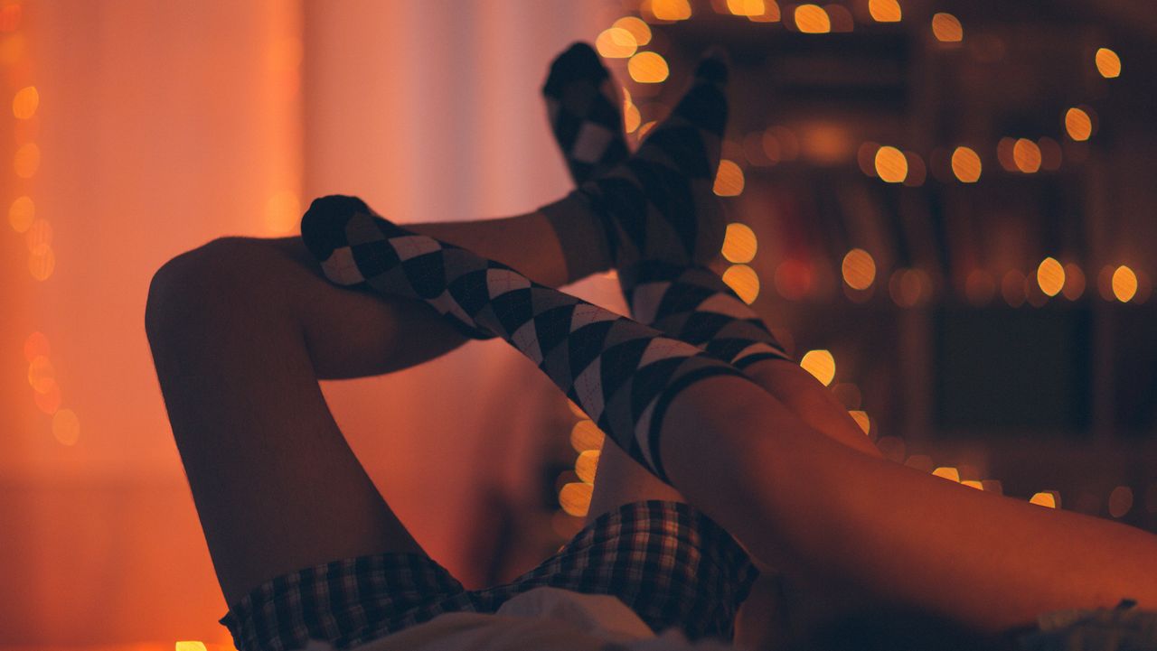 winter sex; couple&#039;s feet in long socks tangled together with sparkly lights in the background