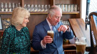 Britain's Camilla, Duchess of Cornwall (L) reacts as she watches Britain's Prince Charles, Prince of Wales take a drink of a pint of Guinness that he had poured, during a visit to the Irish Cultural Centre in London on March 15, 2022, to celebrate the centre's 25th anniversary in the run-up to St Patrick's Day on March 17.