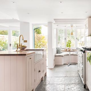 kitchen with pink panelled cabinetry and stone floors
