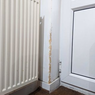 Flaking plaster on white wall next to radiator