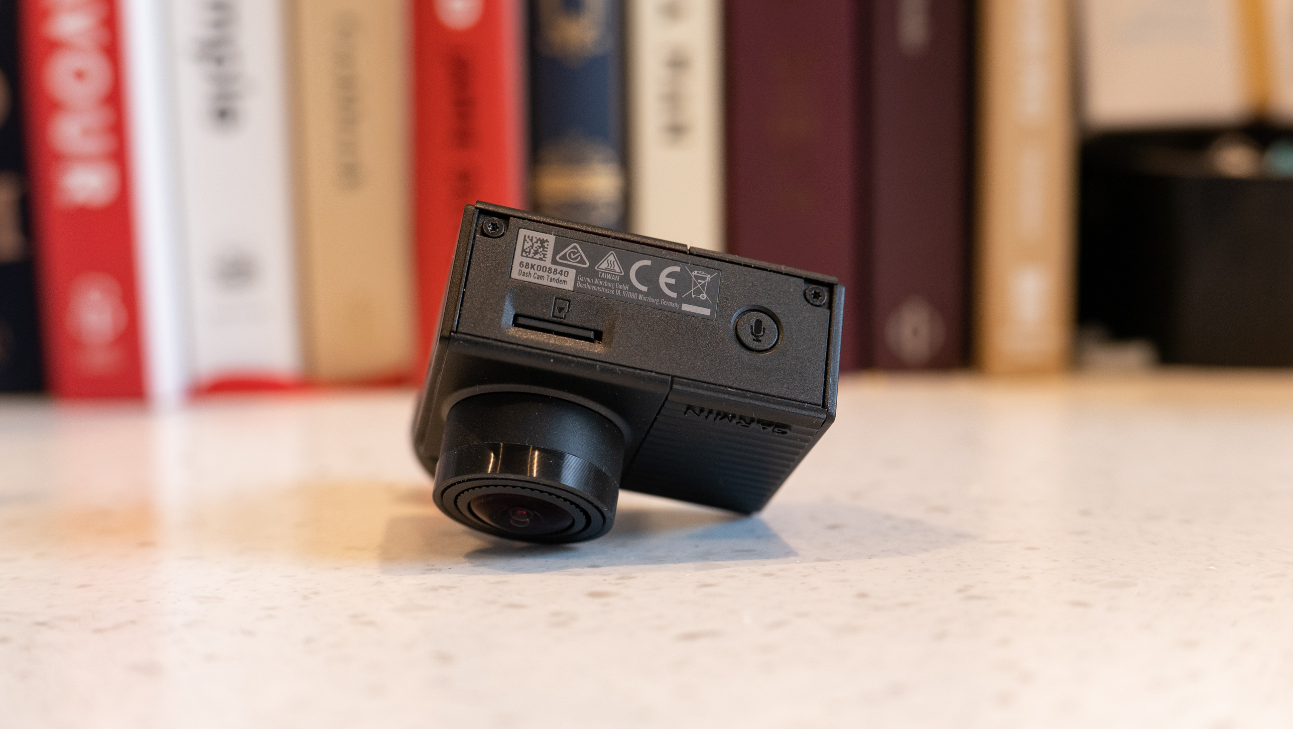 The Garmin Dash Cam Tandem on a table in front of books