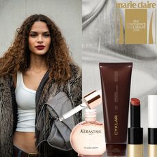 a woman with red lipstick and brown curly hair on a silver background next to beauty product bottles