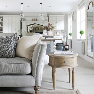 an open plan kitchen diner with shaker-style cabinets and a seating area with a large classic neutral-coloured sofa