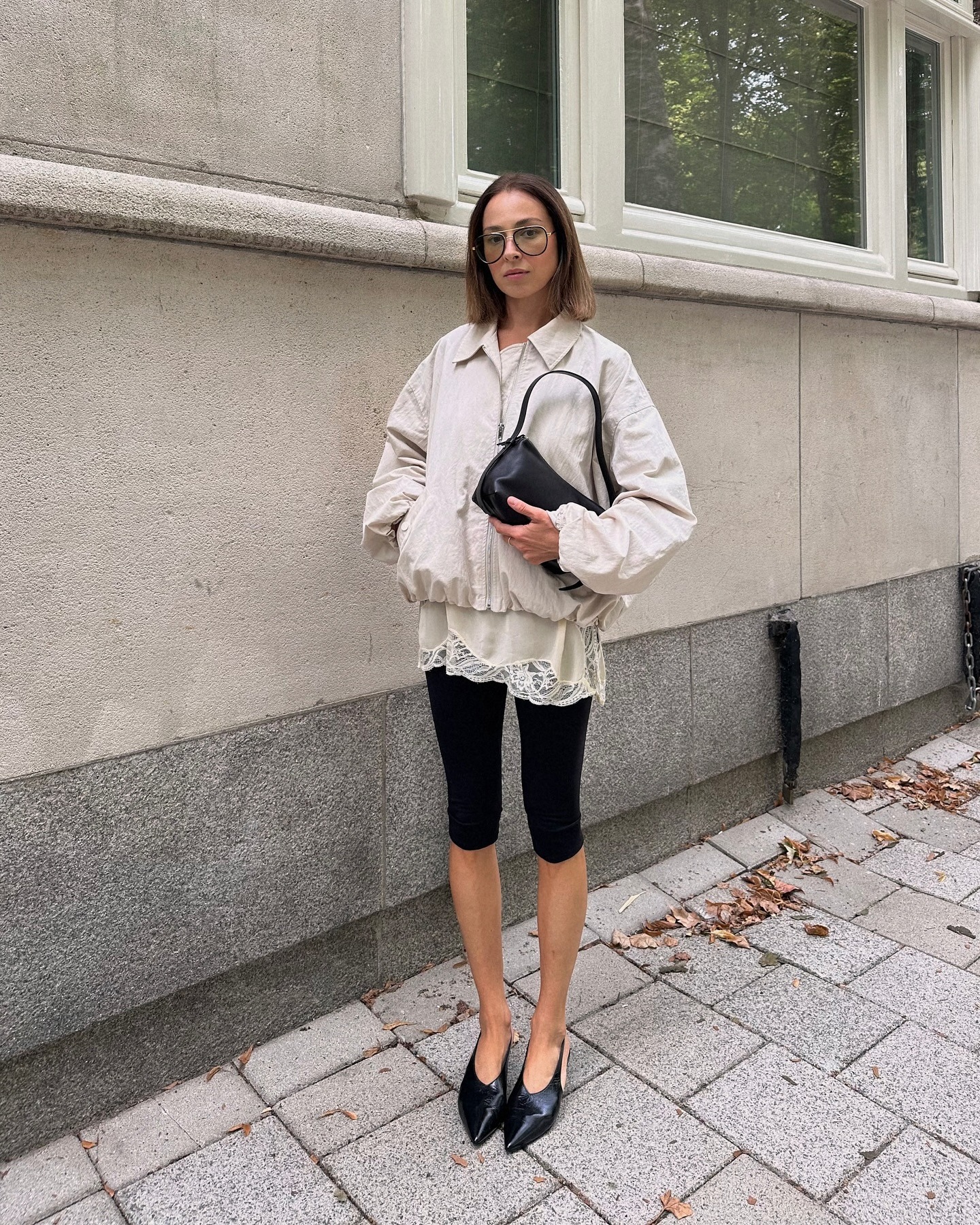 Dilara Ugur wearing a tan windbreaker, white lace top, black capris, and black pointed toe shoes
