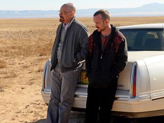 Bryan Cranston as Walter White and Aaron Paul as Jesse Pinkman, stand against a car in the desert.