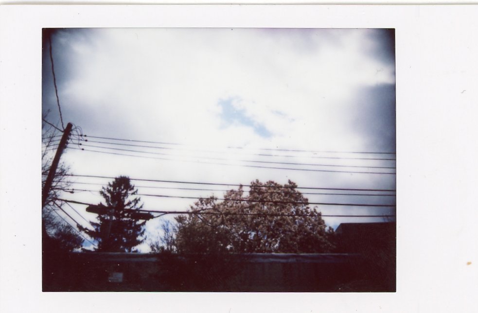 A photograph of the sky and some power lines taken in the neutral filter on the Fujifilm Instax mini 99 with a vignette applied.