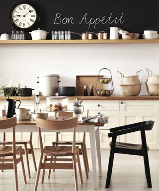 A monochrome kitchen with wooden dining set and chalkboard wall decor with 'Bon Appetit' text