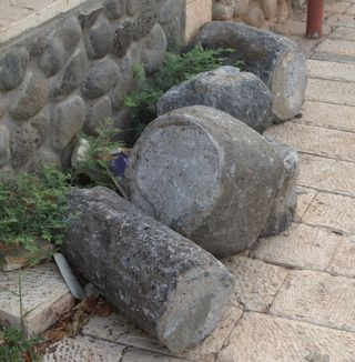 Roman column fragments, along with the top of a rotary quern (for grinding), lying on the side of a road in the modern-day town of Migdal and believed to be part of a newfound ancient town.