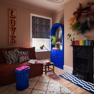 Living room with pink wall paint, bright blue bookshelf and fireplace.