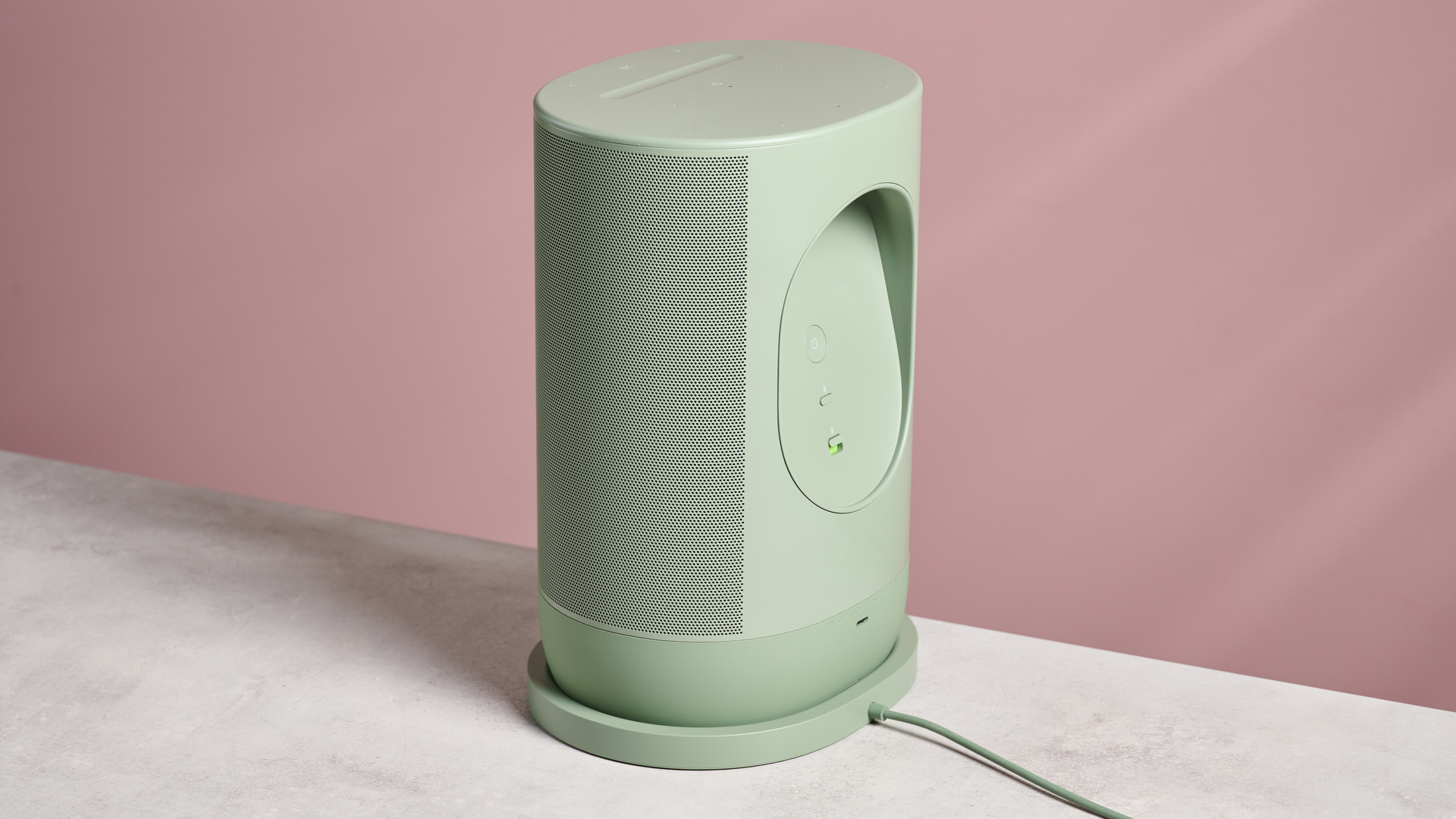 The reverse of the Sonos Move 2 sat in its cradle in front of a pink background.