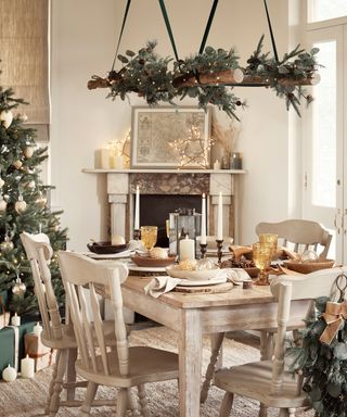 dining table set up for christmas with several chairs, a christmas tree and hanging foliage