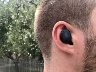 En man som bär ett par Skullcandy Grind True Wireless Earbuds ute på en promenad.