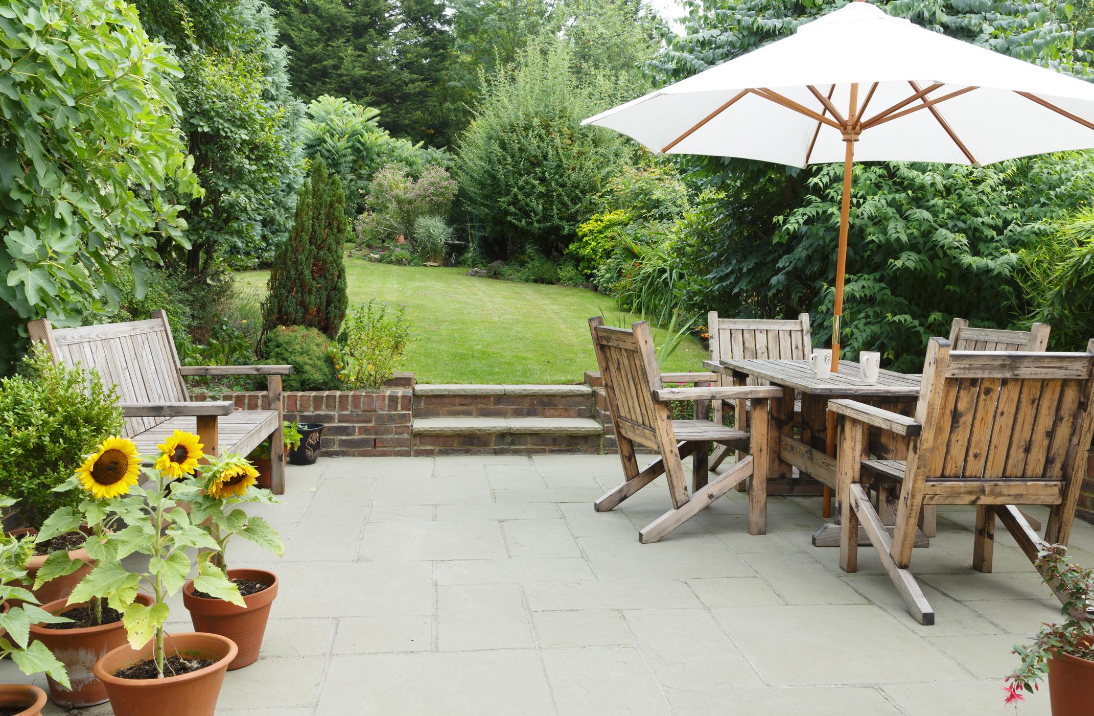  A grey patio with wooden garden table and chairs. 