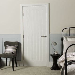 White door in bedroom on panelled wall