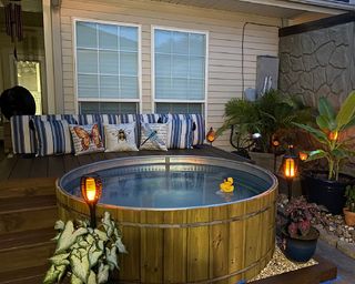 timber clad stock tank pool surrounded by a raised deck with outdoor seating