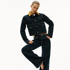 Model poses while wearing a matching denim jacket and jeans.