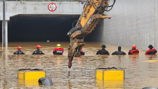 Rescue workers stand in deep water at the entrance of a flooded transport tunnel