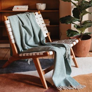 Recycled Wool Waffle Blanket in Sage draped over woven chair