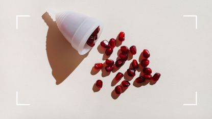 White clear menstrual cup holding pomegranate seeds to represent heavy periods after 40 with clots