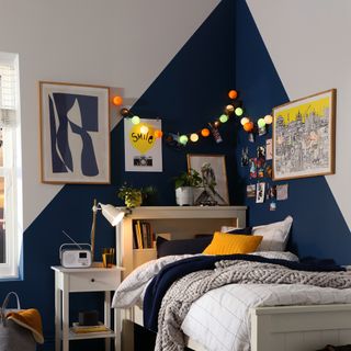 grey and blue bedroom with geometric painted design, fairy lights, artwork and wooden bed