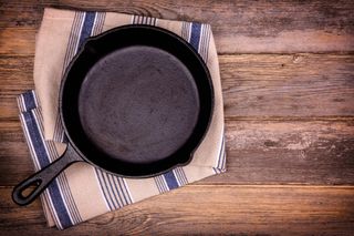 A cast iron skillet on a tea towel on a wooden table