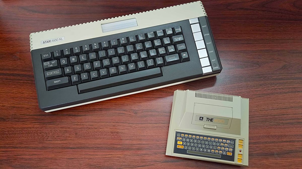 Atari 600XL next to Atari 400 Mini on woodgrain desk.