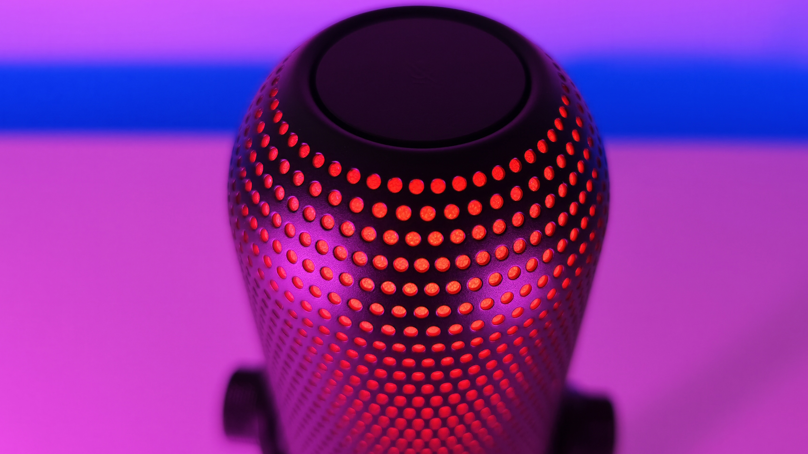Top-down view of the Razer Seiren V3 Chroma microphone grille glowing red to indicate it is muted.