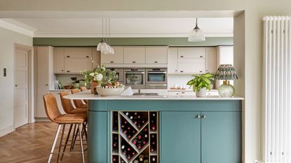 Open-plan kitchen-diner with blue units and peninsula island with bar stools