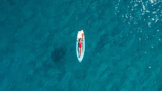 A woman sunbathing on a paddle board in a the sea